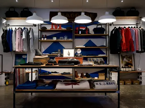 Interior de una tienda de ropa con estanterías y prendas colgadas